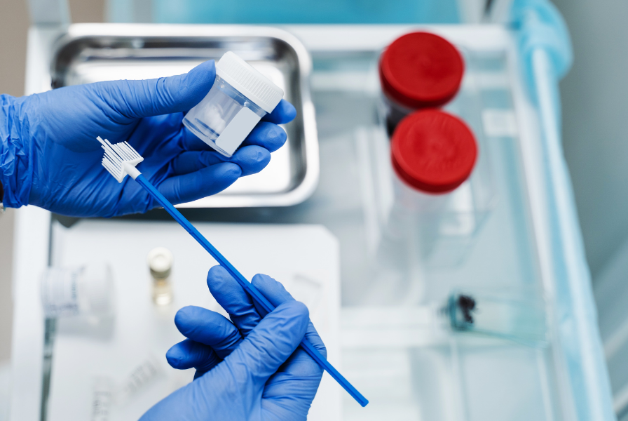 Gloved hands holding a sample-collection swab and container.