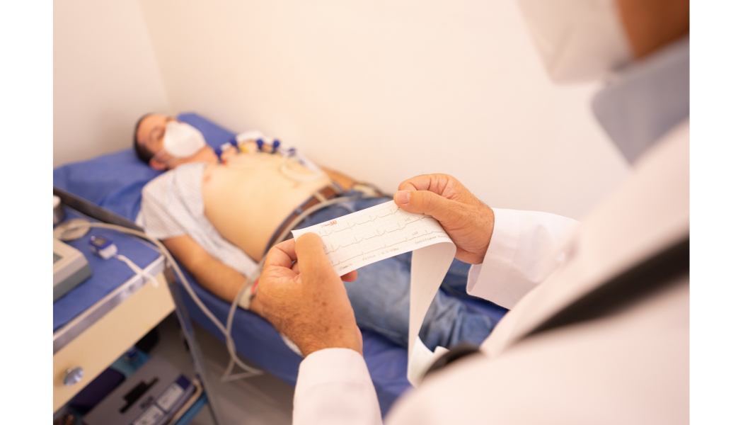 Clinician reviewing an electrocardiogram printout beside a patient.