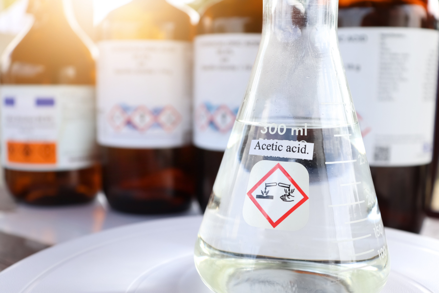 Laboratory flask labeled acetic acid with a corrosive hazard symbol.