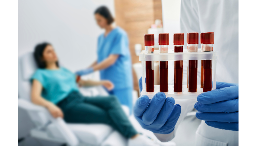 Blood sample tubes held by gloved hands.