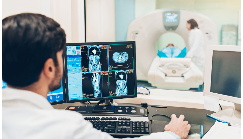 Clinician viewing cross-sectional imaging beside an imaging scanner.