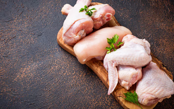 Raw chicken pieces on a board.