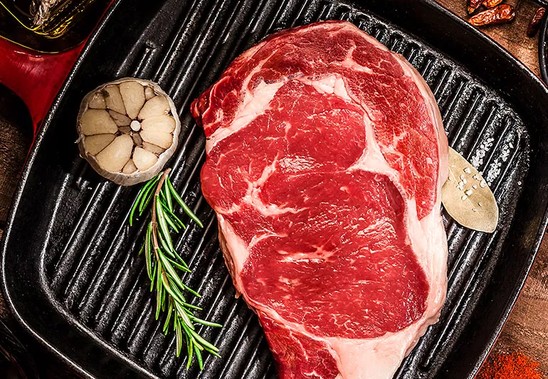 Raw beef steak with garlic and rosemary.